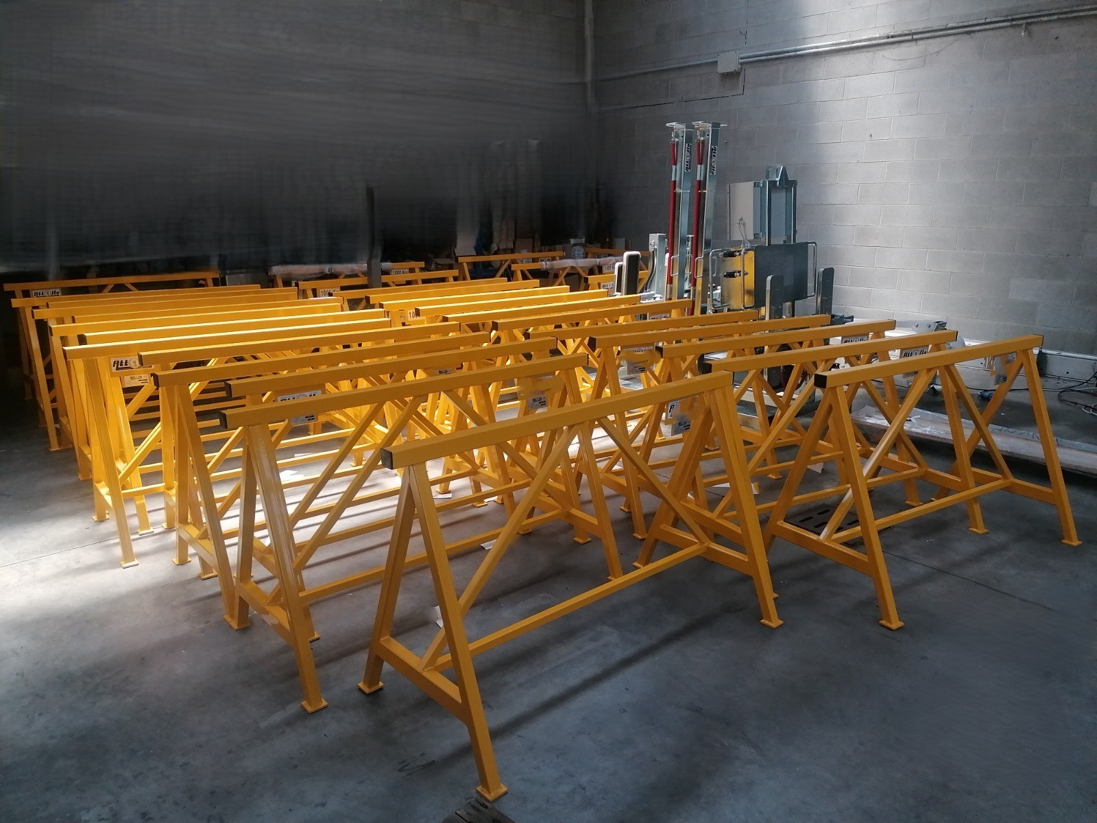 Serie di cavalletti industriali certificati CE verniciati in giallo pronti per la consegna in un capannone